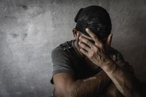 Men who show stress and loneliness, Homeless man drug  addict sitting alone and depressed  at an abandoned house feeling anxious and lonely, social documentary concept, Copy space photo