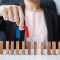 Business woman hand holding magnet and pulling man wooden figure from the crowd block. Business, Human resource management, Recruitment, Teamwork, strategy, toxic people and leadership Concepts photo