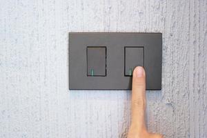 el dedo masculino de primer plano se enciende o apaga en el interruptor de luz en la pared en casa. conceptos de ahorro de energía, energía, electricidad y estilo de vida foto