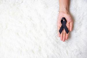 Melanoma and skin cancer, Vaccine injury awareness month and rest in peace concepts. Man holding black Ribbon on white bed background photo