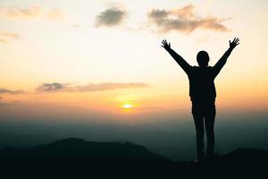 silueta de una mujer rezando en la montaña, rezando manos con fe en la religión y creencia en dios. foto