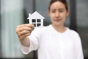 mujer sosteniendo un modelo de casa. inversión inmobiliaria y concepto de bienes raíces financieros de hipoteca de casa foto
