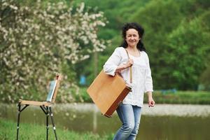 Blooming tree behind. Mature painter with case of instruments have a walk in the beautiful spring park photo