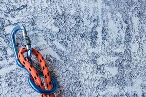 Orange colored knot. Isolated photo of climbing equipment. Part of carabiner lying on the white and grey colored surface