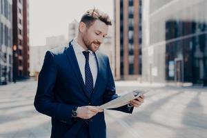 Business owner reading positive news in newspaper while walking to work photo