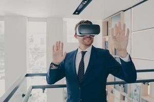 Smiling office worker in vr headset touching air and gesturing while working in virtual reality photo