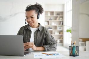 Biracial young girl student in headset learning online at laptop at home. Distance education photo