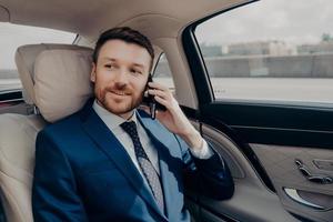 Young good looking businessman taking ride to conference while talking on phone photo