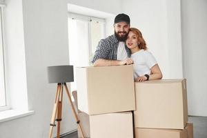 Near the windows. Happy couple together in their new house. Conception of moving photo