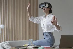 Young amazed businesswoman in virtual reality glasses testing innovative method for business photo