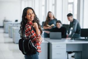 Holding black bag. Group of young people in casual clothes working in the modern office photo