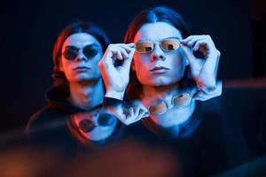 Artificial lighting. Portrait of twin brothers. Studio shot in dark studio with neon photo