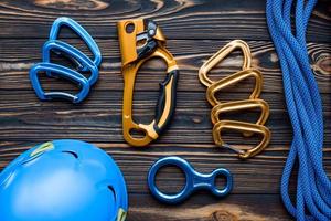 Strong blue colored protective helmet. Isolated photo of climbing equipment. Parts of carabiners lying on the wooden table