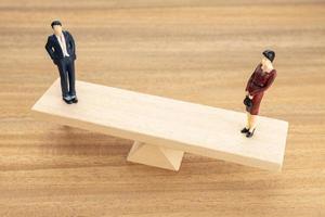 Gender equality concept. Man and woman figurine on wooden seesaw photo