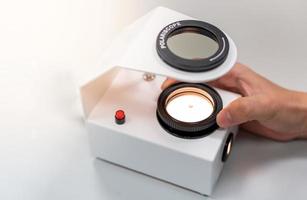 The Gemologist expertise in her laboratory fix the value of precious stone of the polariscope. photo