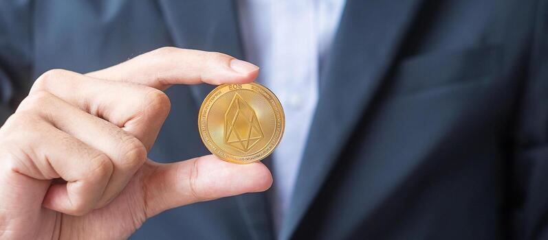 man hand holding gold EOS coin cryptocurrency, Crypto is Digital Money within the blockchain network, is exchanged using technology and online exchange. Decentralized Financial concept photo