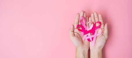 October Breast Cancer Awareness month, adult Woman hand holding Pink Ribbon on pink background for supporting people living and illness. International Women, Mother and World cancer day concept photo