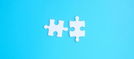couple of white puzzle jigsaw pieces on blue background. Concept of solutions, mission, success, goals, cooperation, partnership, strategy and puzzle day photo