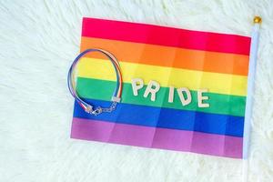 lgbtq, bandera del arco iris y pulsera sobre fondo blanco. apoyar la comunidad lesbiana, gay, bisexual, transgénero y queer y el concepto del mes del orgullo foto