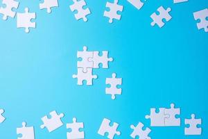 Group of white puzzle jigsaw pieces on blue background. Concept of solutions, mission, success, goals, cooperation, partnership, strategy and puzzle day photo