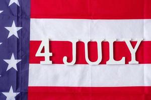 Texto del cuatro de julio sobre el fondo de la bandera de los Estados Unidos de América. EE.UU. fiesta de la independencia y los conceptos de celebración foto