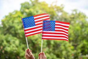 hand holding United States of America flag on blue sky background. USA holiday of Veterans, Memorial, Independence and Labor Day concept photo