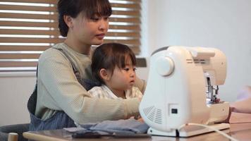 padres e hijos usando una máquina de coser video