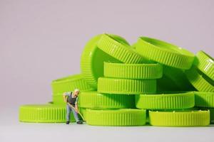 Worker figure standing on plastic cap. Recycle material concept. photo