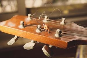 la figura del trabajador técnico arreglando viejas cuerdas de guitarra. foto