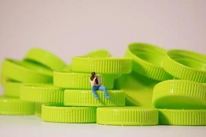 figura de hombre sentada en una tapa de plástico. reciclar el concepto de material. foto