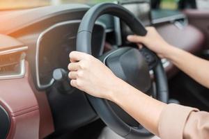 woman driver driving a car on the road, hand controlling steering wheel in electric modern automobile. Journey, trip and safety Transportation concepts photo