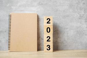 2023 feliz año nuevo con cuaderno en blanco y número de madera. concepto de cuenta regresiva, resolución, objetivos, plan, acción y misión foto