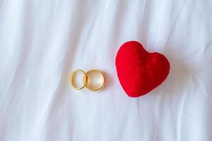 decoración en forma de corazón y anillo de compromiso de pareja dorado sobre fondo blanco. concepto de amor, juntos y feliz día de san valentín foto