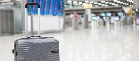 bolsa de equipaje en la terminal del aeropuerto internacional, maleta con ruedas con tablero de información en el fondo del aeródromo. conceptos de transporte, seguros, viajes y vacaciones foto