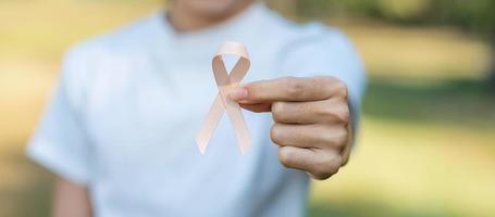 September Uterine Cancer Awareness month, woman hand holding Peach Ribbon for supporting people living and illness. Healthcare and World cancer day concept photo