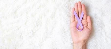 World cancer day. Woman hand hoy Lavender purple ribbon for supporting people living and illness. Healthcare and medical concept photo