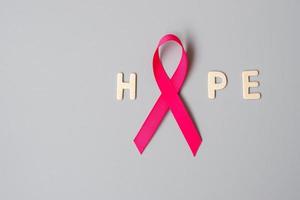 octubre mes de concientización sobre el cáncer de mama, cinta rosa con texto de esperanza sobre fondo gris para apoyar a las personas que viven y están enfermas. concepto del día internacional de la mujer, la madre y el día mundial del cáncer foto