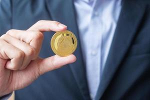 Business man hand holding gold Dogecoin cryptocurrency, Crypto is Digital Money within the blockchain network, is exchanged using technology and online exchange. Decentralized Financial concept photo