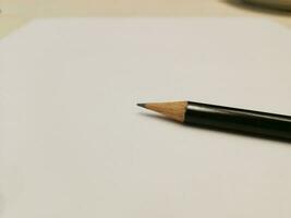 The pencil is placed right side on the paper. photo