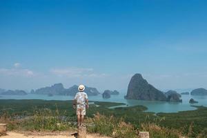 Happy traveler man enjoy Phang Nga bay view point, alone Tourist standing and relaxing at Samet Nang She, near Phuket in Southern Thailand. Southeast Asia travel, trip and summer vacation concept photo