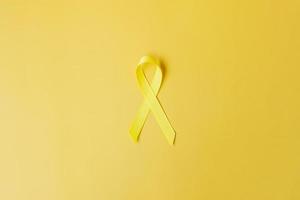cinta amarilla sobre fondo amarillo para apoyar a las personas que viven y están enfermas. día de prevención del suicidio de septiembre, mes de concientización sobre el cáncer infantil y concepto del día mundial contra el cáncer foto