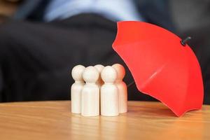 Businessman hand holding umbrella and cover man wooden from crowd of employees. People, Business, Human resource management, Life Insurance, Teamwork and leadership Concepts photo