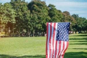 mujer que viaja con la bandera de los Estados Unidos de América en el parque al aire libre. fiesta de los veteranos en estados unidos, memorial, independencia y concepto del día del trabajo foto