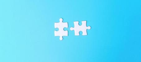 couple of white puzzle jigsaw pieces on blue background. Concept of solutions, mission, success, goals, cooperation, partnership, strategy and puzzle day photo