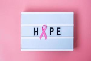 mes de concientización sobre el cáncer de mama de octubre, cinta rosa en la caja de luz con fondo de texto de esperanza para apoyar a las personas que viven y están enfermas. concepto del día internacional de la mujer, la madre y el día mundial del cáncer foto