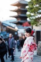 una joven turista con kimono disfruta en el área de la pagoda de yasaka cerca del templo kiyomizu dera, kyoto, japón. chica asiática con estilo de cabello en ropa tradicional japonesa en la temporada de follaje de otoño foto