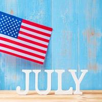 texto de julio y bandera de los estados unidos de américa sobre fondo de mesa de madera. EE.UU. fiesta de la independencia y los conceptos de celebración foto