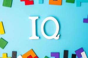 IQ text with colorful wood puzzle pieces, geometric shape block on blue background. Concept of intelligence quotient and logic thinking photo