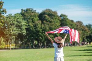mujer que viaja con la bandera de los Estados Unidos de América en el parque al aire libre. fiesta de los veteranos en estados unidos, memorial, independencia y concepto del día del trabajo foto