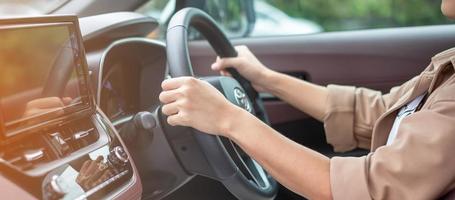 woman driver driving a car on the road, hand controlling steering wheel in electric modern automobile. Journey, trip and safety Transportation concepts photo